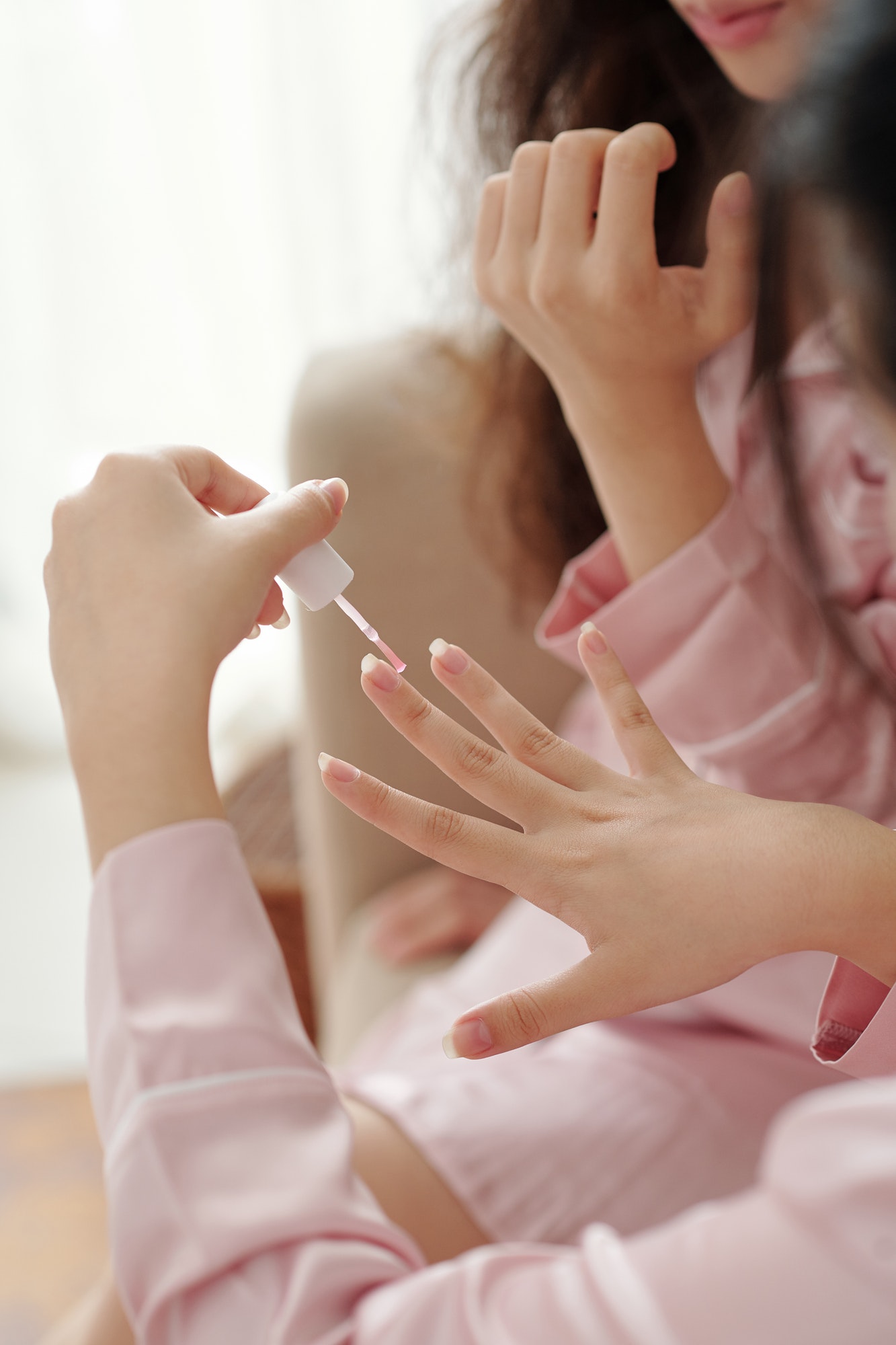woman applying transparent base coat on her nails